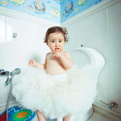 Young child sat on the toilet and wearing a tulle skirt