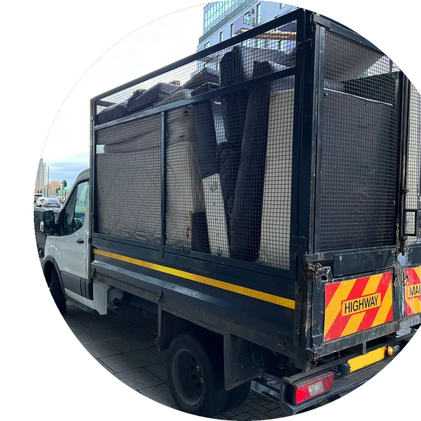 A maintenance truck loaded with equipment and furniture on a city street.