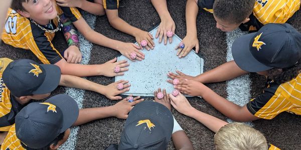 Youth baseball team showing championship rings around home plate.