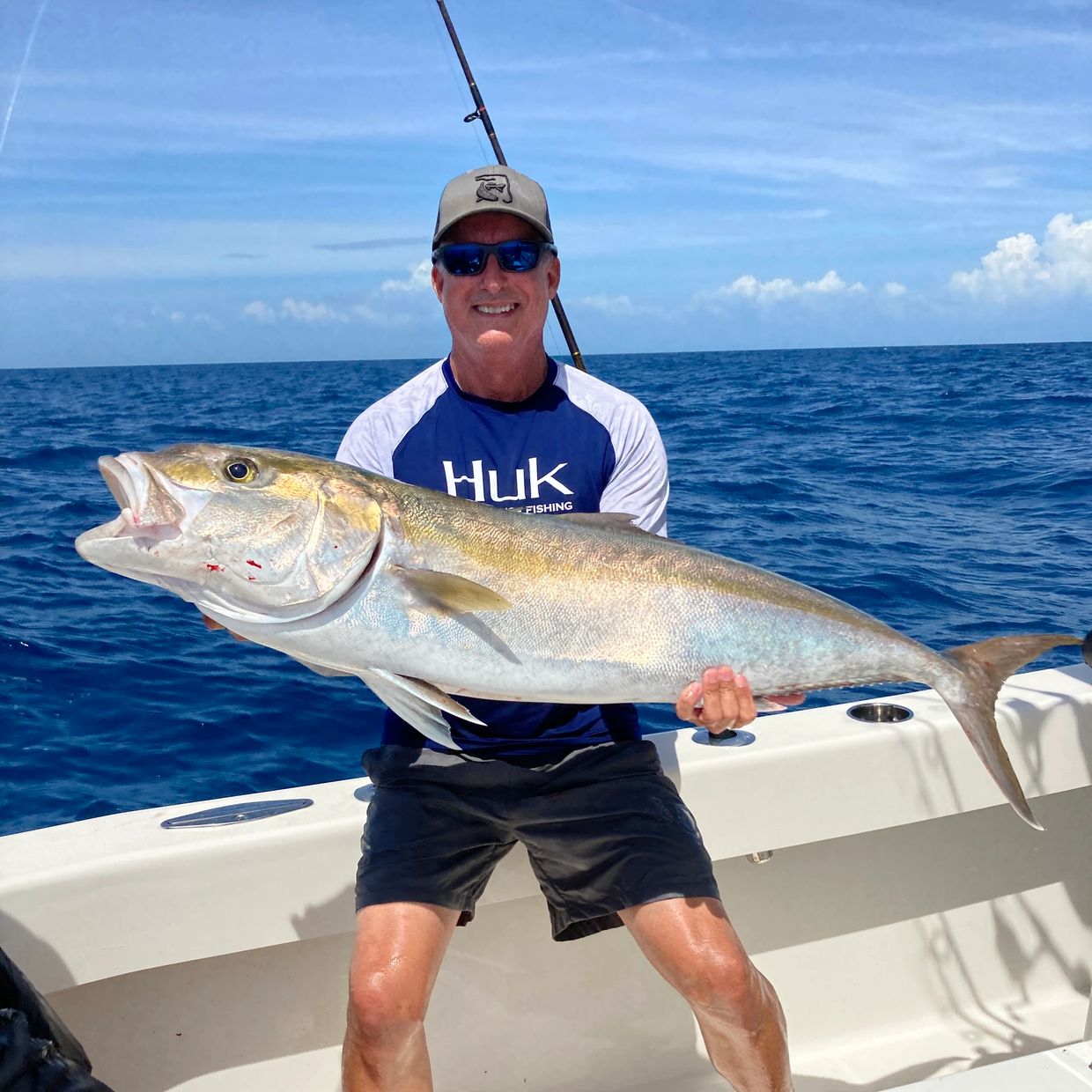 Man proudly holding a large fish on a boat in the ocean.