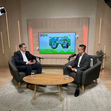 Two men in suits having a professional discussion in a modern studio setting.