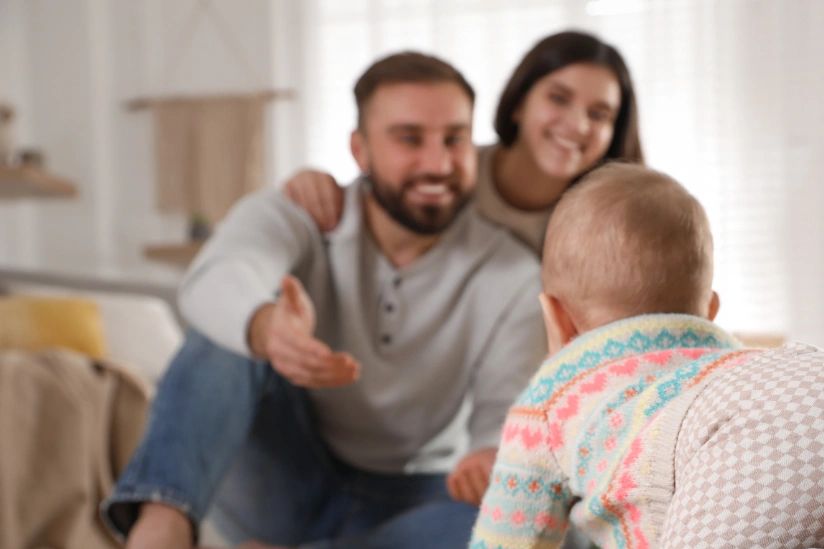 Parents watching their baby crawl.