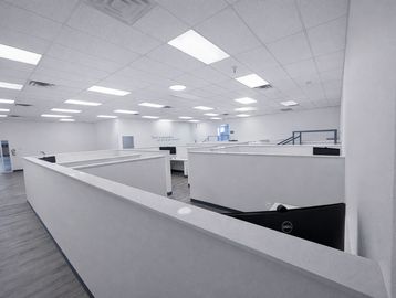 Empty office cubicles under bright white ceiling lights.