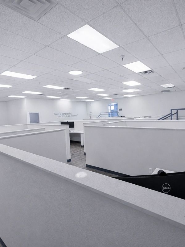Bright, empty office cubicles with white walls and ceiling lights.