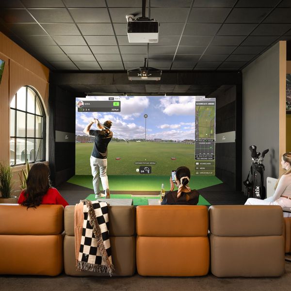 People enjoying an indoor golf simulator in a cozy room.