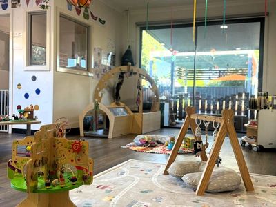 A bright and cozy playroom filled with wooden toys and soft cushions.