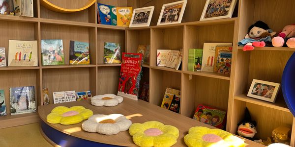 Cozy children's reading corner with flower cushions and colorful books.