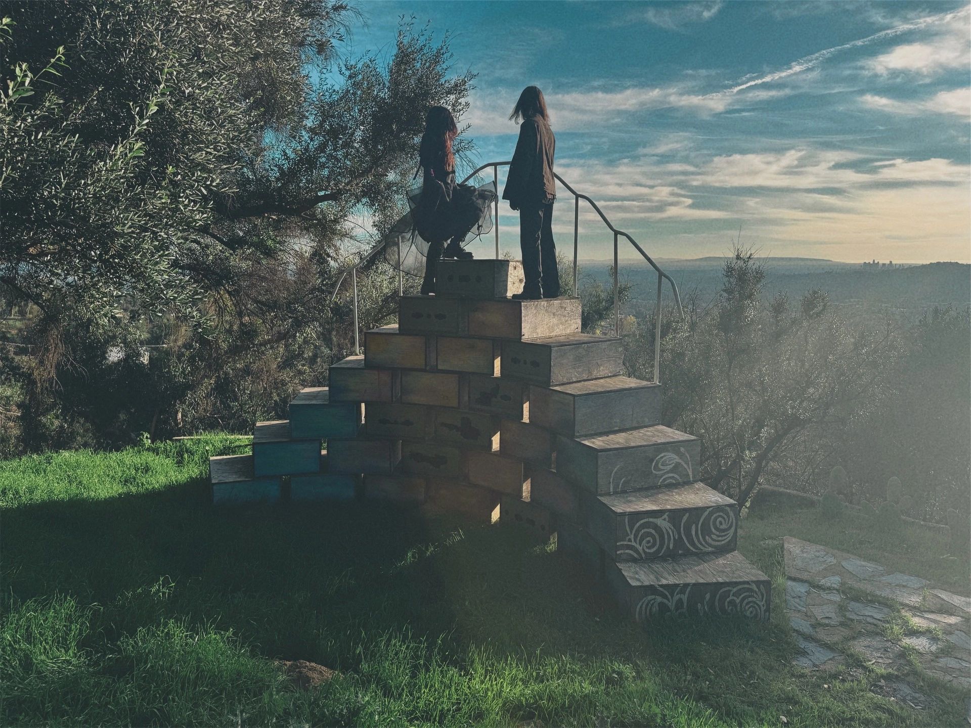 Two people standing on a wooden staircase outdoors.