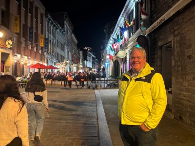 Man smiling on a lively city street at night.