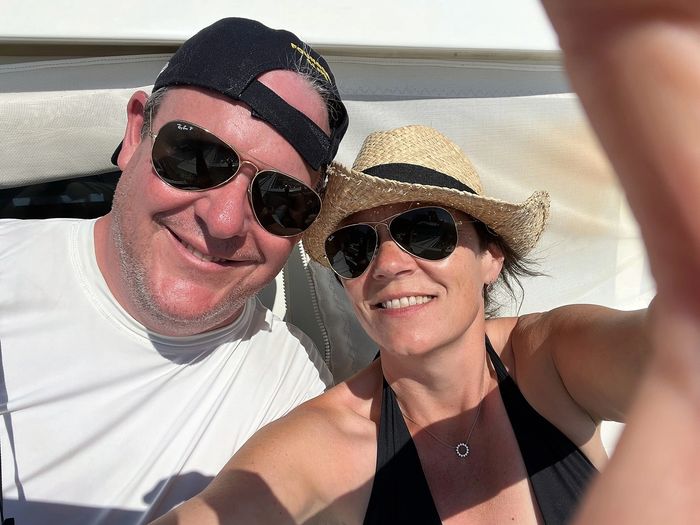 Happy couple wearing sunglasses and hats taking a sunny selfie.