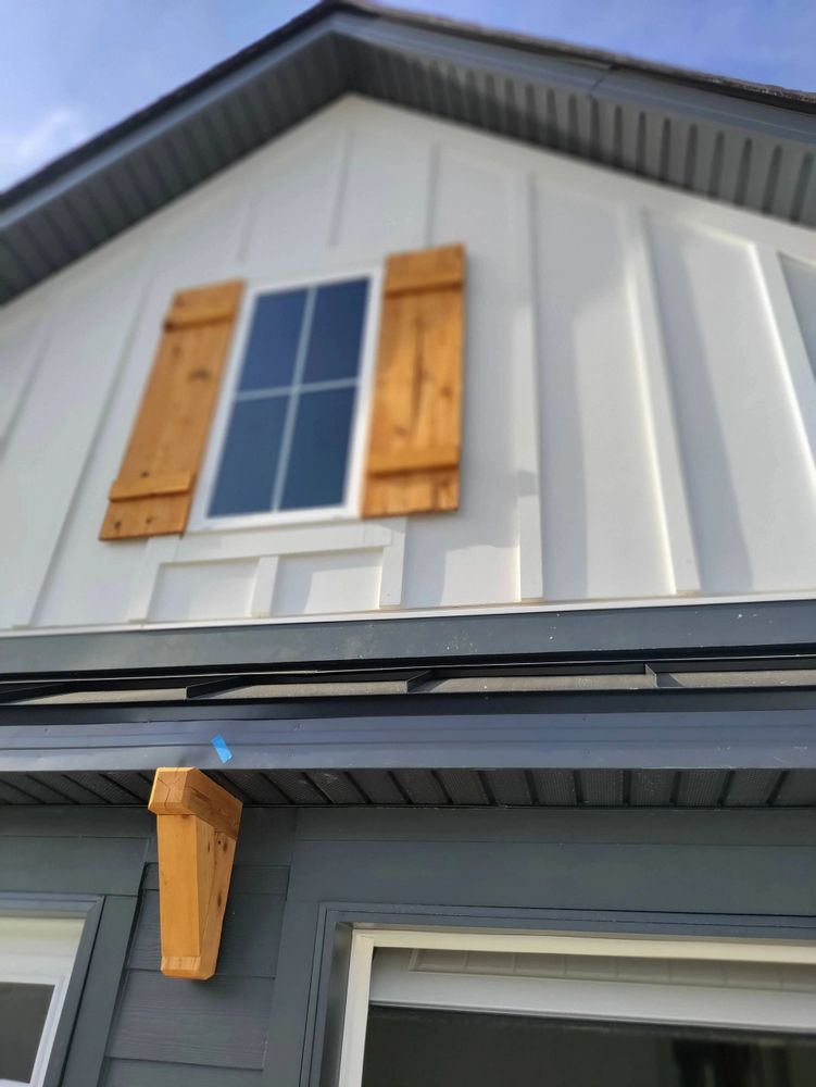 Board & Batton Fiber Cement Siding with Vinyl Soffit & Composite Trim Boards. Cedar Shutters.