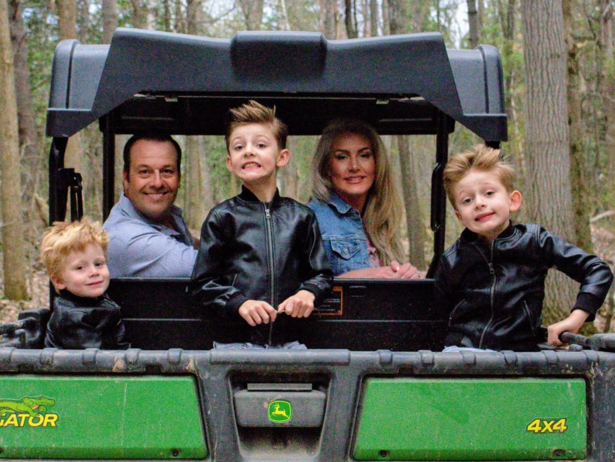 Family riding an off-road vehicle in a forest.