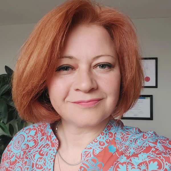 Woman with red hair wearing a floral top.