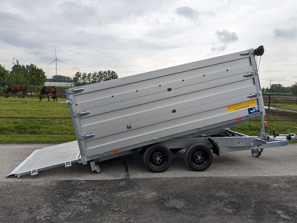 A tilted silver utility trailer with a ramp lowered on a rural road.