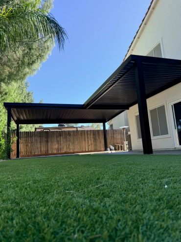 Modern backyard patio cover under clear blue sky.