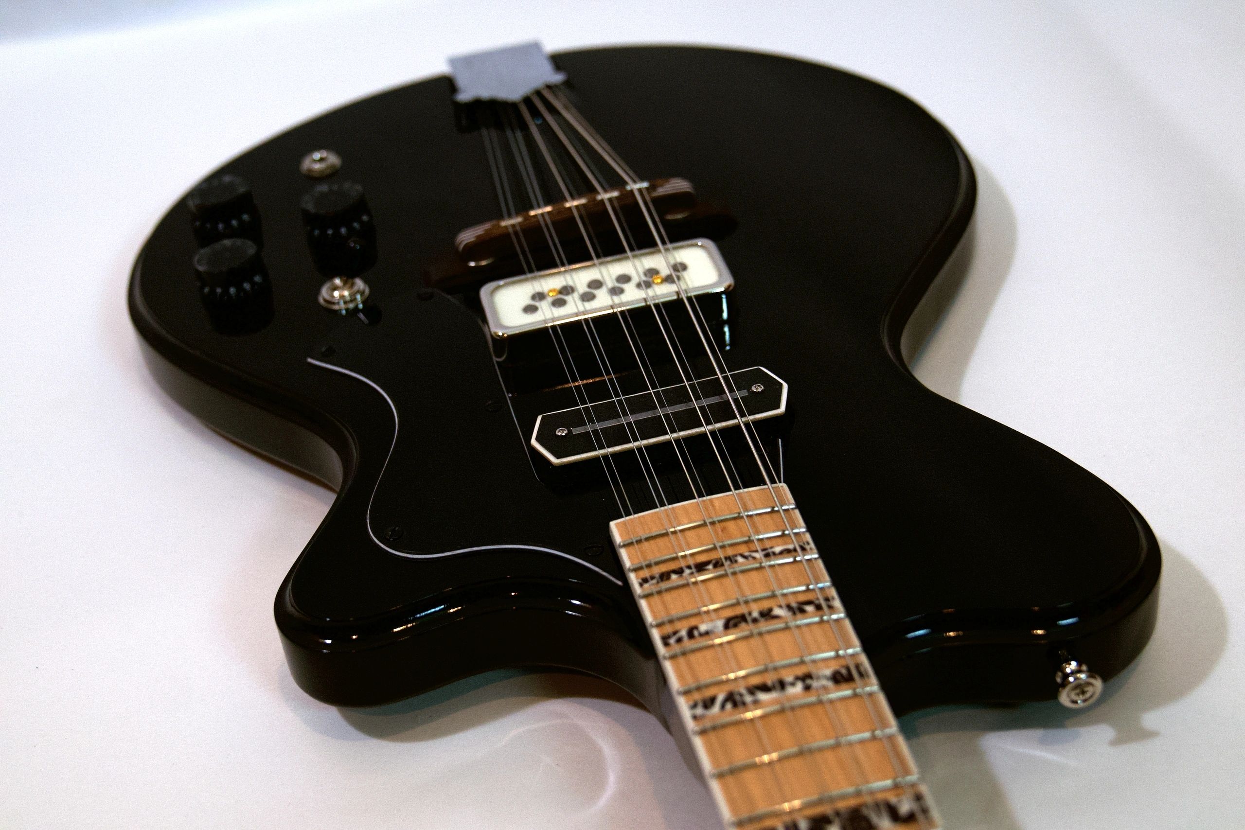 Close-up of a sleek black electric guitar body and neck.