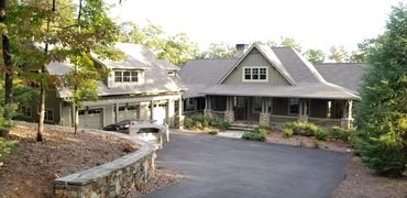 Spacious house with large driveway surrounded by trees.