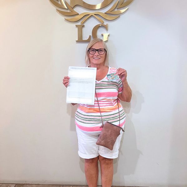 Woman holding a document and a card, smiling.