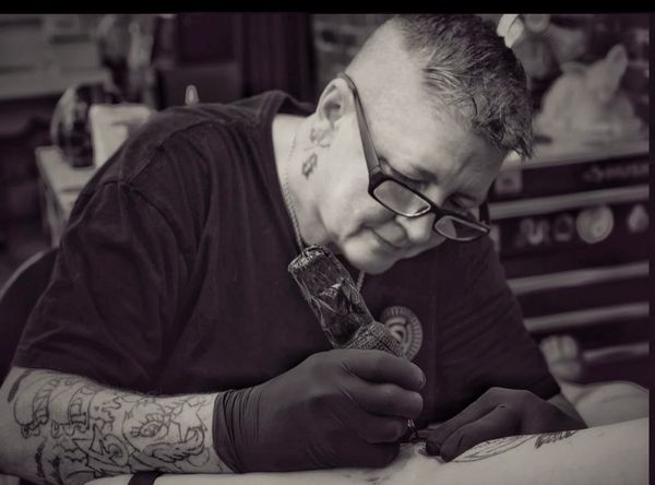 Tattoo artist focused on creating detailed ink art in a studio.