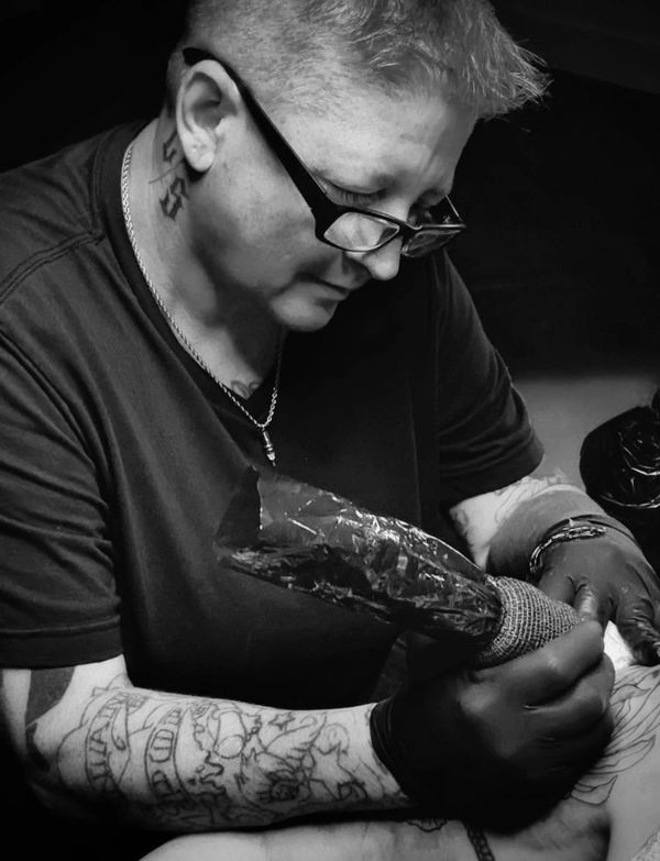 Tattoo artist focused on creating a detailed tattoo in black and white.