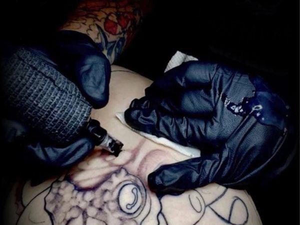 Close-up of a tattoo artist creating an octopus tattoo on skin.