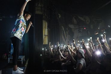 Singer engaging an enthusiastic crowd with raised lights at a concert.