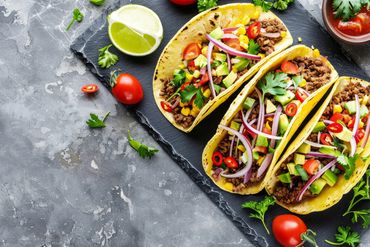 A tempting trio of tacos, juicy meat, ripe tomatoes, and zesty onions, perfect for a tasty meal.