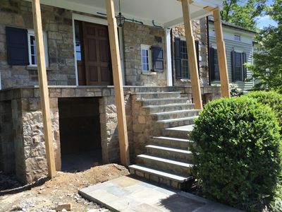 Stone house with stairs and wooden supports under renovation.
