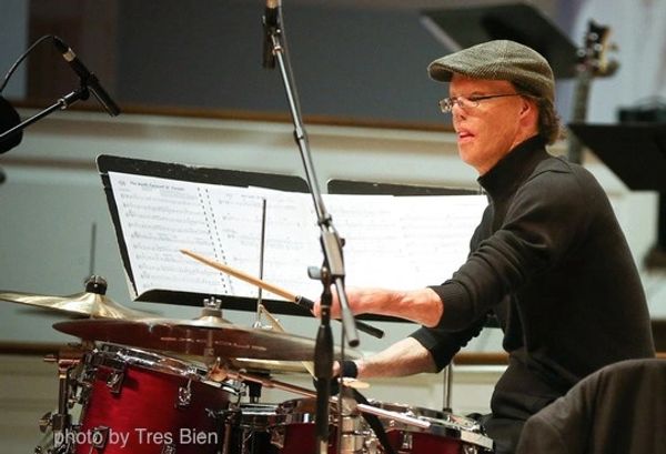 Musician playing drums intensely in a studio.