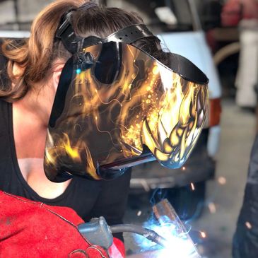 Person wearing a creative dog-shaped welding helmet while welding.