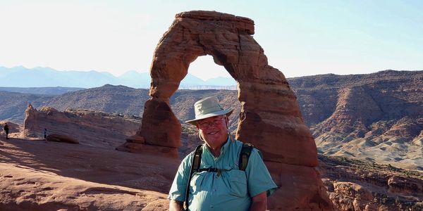 Man posing in front of Delicate Arch in Arches National Park.