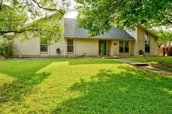 Single-story house with a green lawn and trees in front.