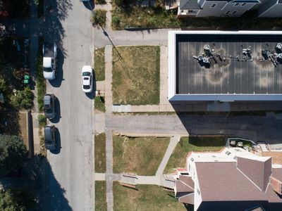 Aerial view of a residential street with parked cars and houses.