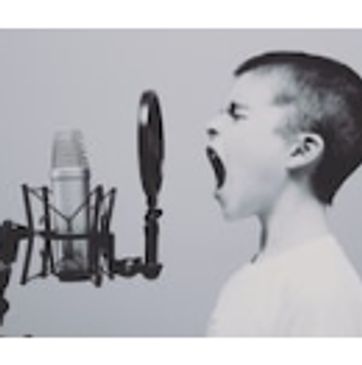 This is an image of a young boy singing into the microphone and the image is black and white.