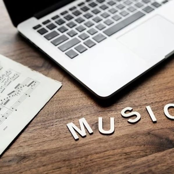 The word music laying on desk besides a laptop computer.