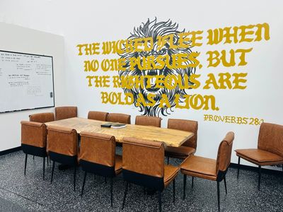 Conference room with brown chairs and a biblical wall quote about the wicked and the righteous.
