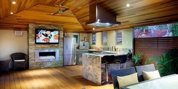 Modern outdoor kitchen and lounge with wood ceiling and flooring.