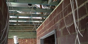 Interior of a building under construction showing exposed brick walls and wiring.