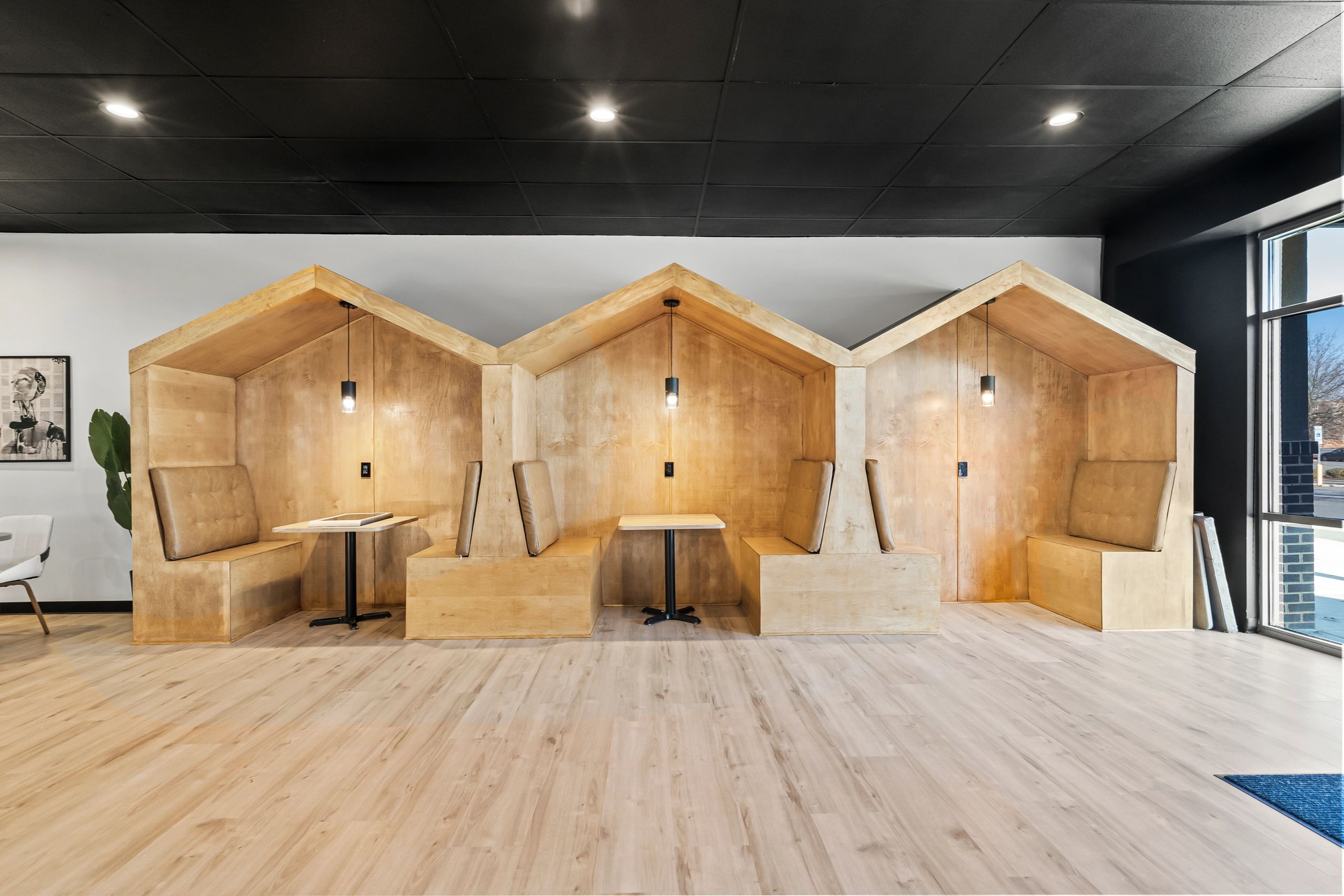 Modern wooden booth seating with pendant lights in a stylish room.