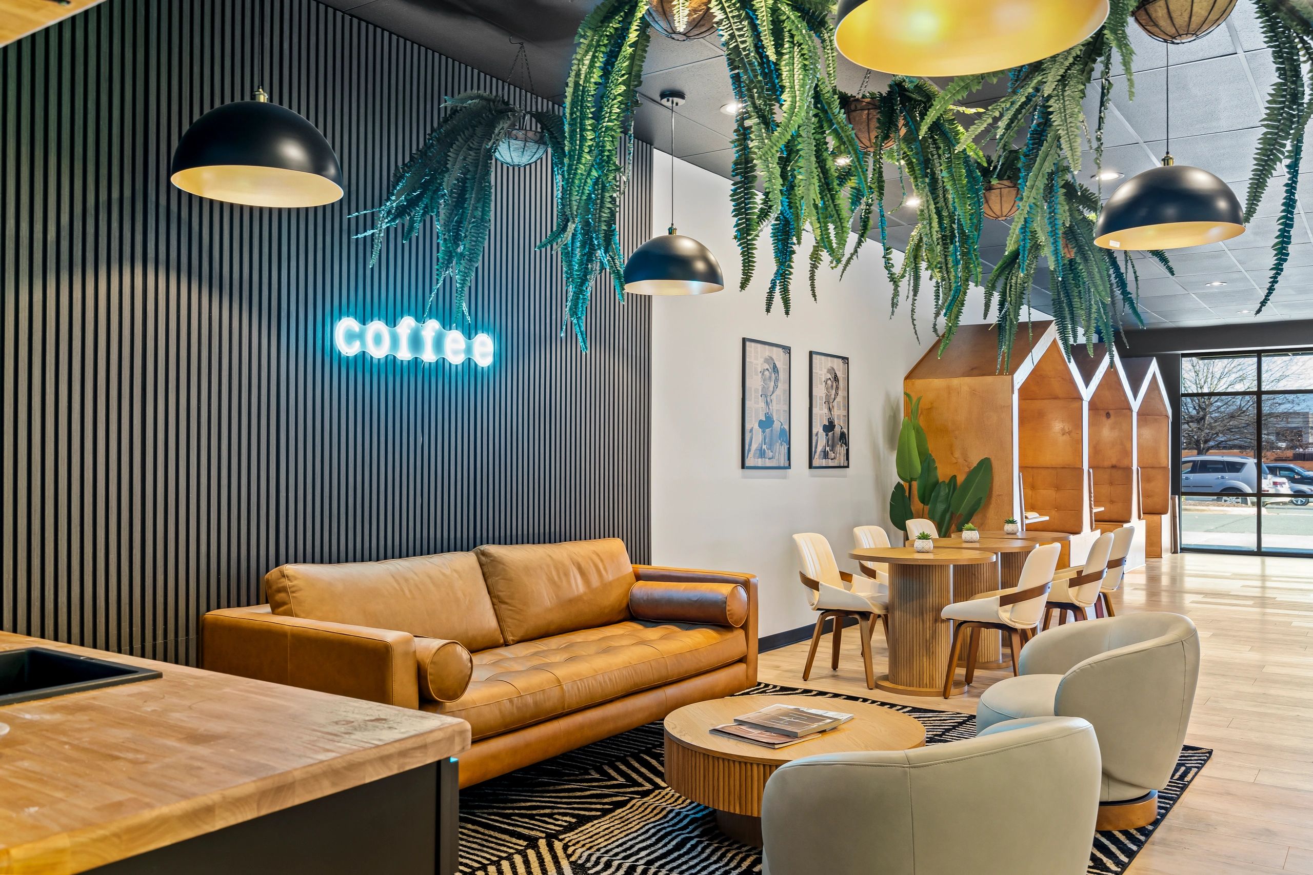 Cozy coffee lounge with leather sofa, hanging plants, and wooden furniture.