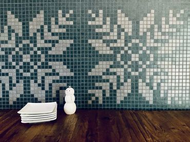 Snowflake mosaic mural behind rustic dining table with dessert plates and snowman salt-shaker