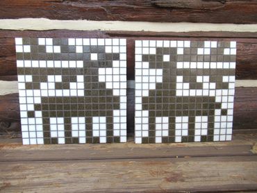 Mosaic installation of two reindeer facing each-other outside a log cabin