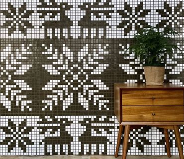 Mosaic mural with Nordic patterns featuring reindeer and snowflakes behind mid-century nightstand