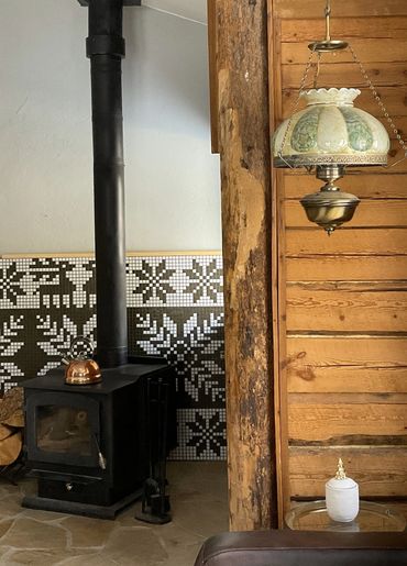 Mosaic mural with Nordic patterns featuring reindeer and snowflakes, behind wood-burning fireplace