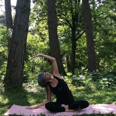 süße Elfenfrau in einer Yogaposition im Park