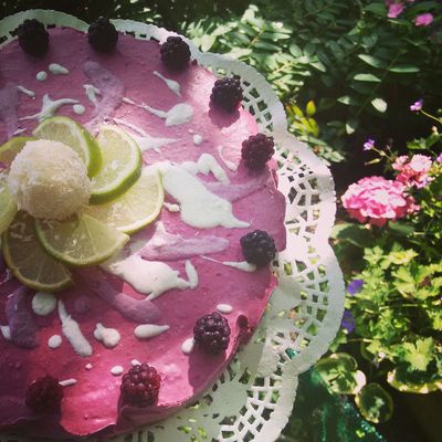 Purple cake decorated with lime slices and blackberries on a doily.