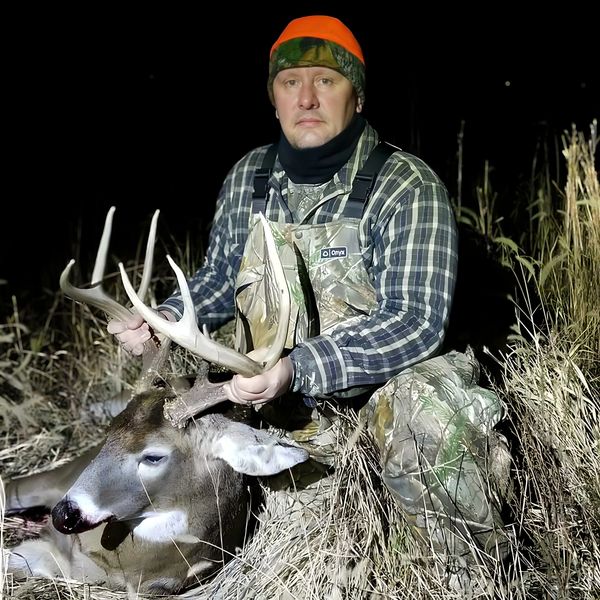 Hunter holding a large buck deer at night.