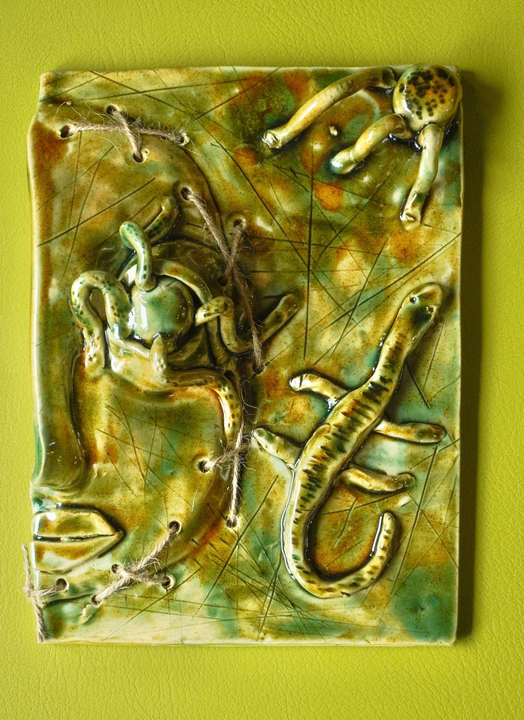 Ceramic art of reptiles on a green background.