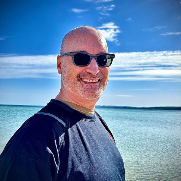 Smiling man wearing sunglasses at the beach.
