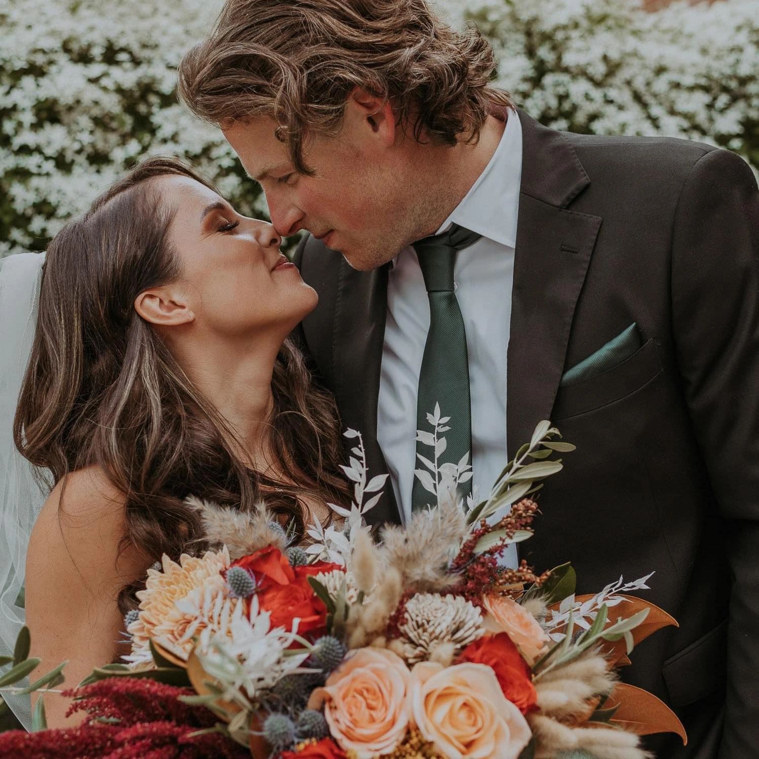 Bride and Groom hugging while holding onto the bridal bouquet
Photo by Montana Lane Photography